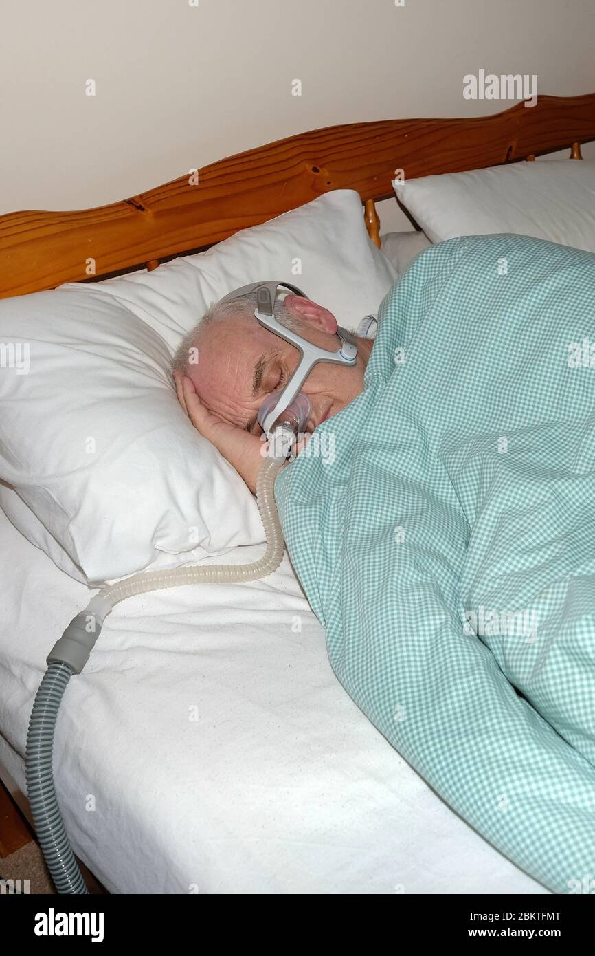 Maggio 2020 - uomo maturo addormentato veloce indossando la maschera di una macchina CPAP di apnea del sonno @ 05.30 Foto Stock