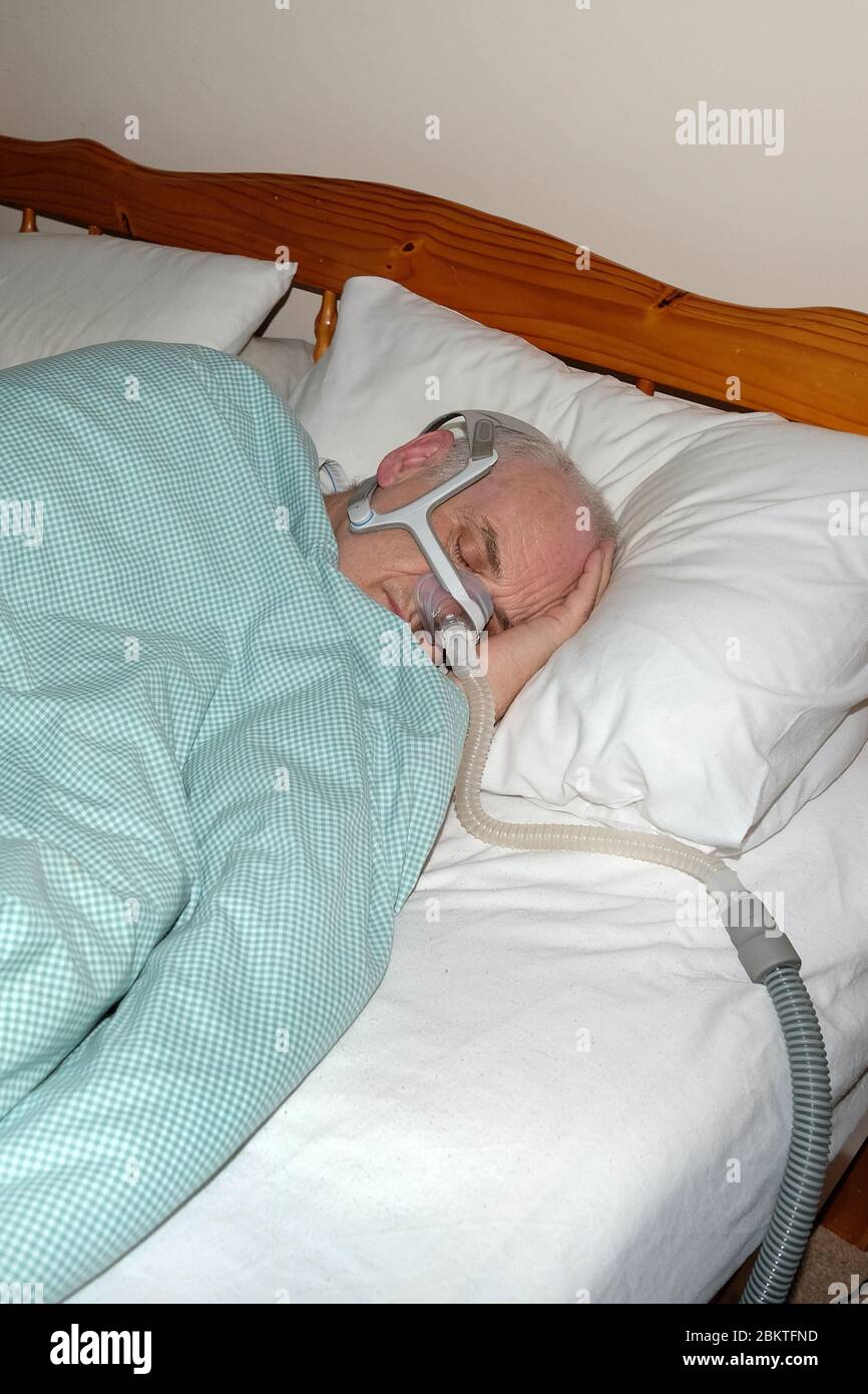 Maggio 2020 - uomo maturo addormentato veloce indossando la maschera di una macchina CPAP di apnea del sonno @ 05.30 Foto Stock