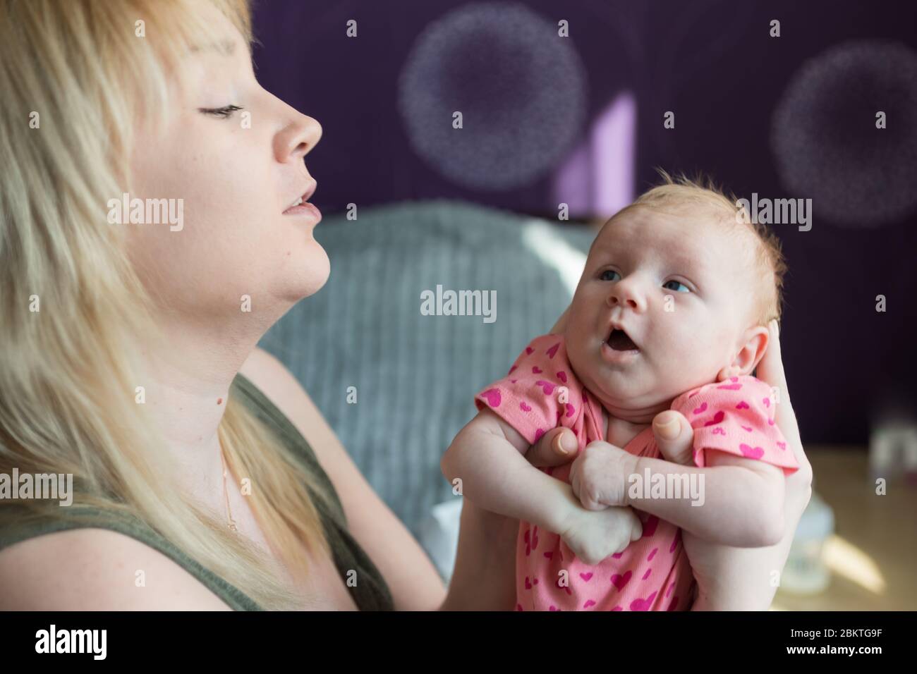 Una donna tiene una bambina neonato tra le braccia. La figlia guarda sua madre. Le madri amano e si preoccupano. Le prime emozioni Foto Stock