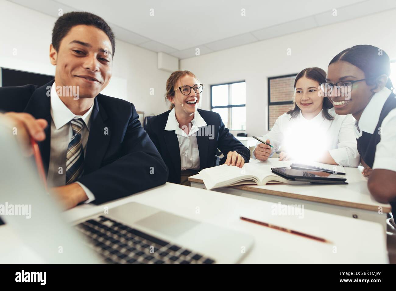 Gruppo di studenti che studiano insieme su un notebook in classe. Ragazzi e ragazze in uniforme che lavorano su un incarico scolastico. Foto Stock