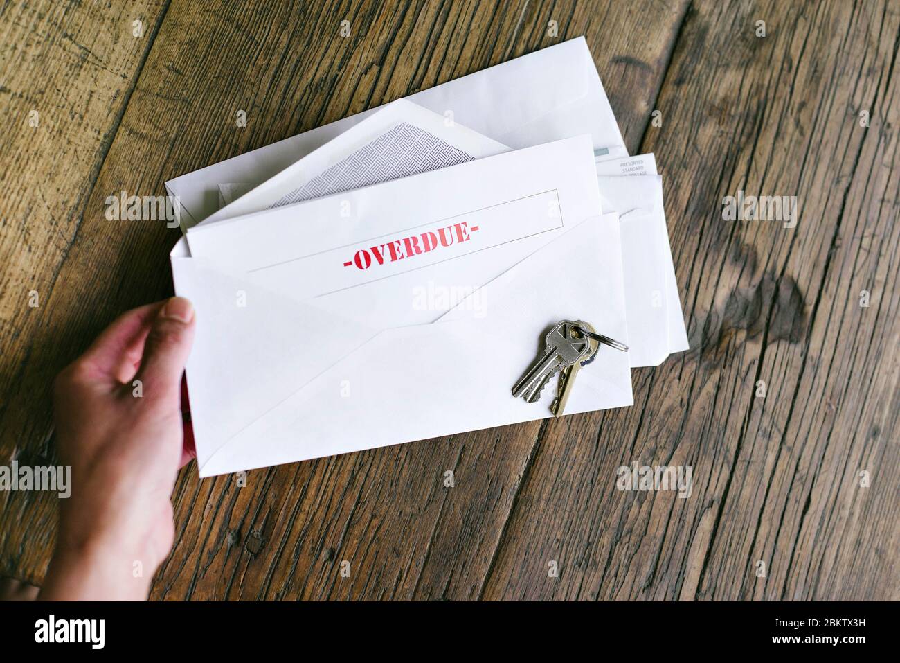 Le mani di una donna tengono una lettera con la scritta in ritardo in una busta - chiavi - Tabella - pagamento tardivo Foto Stock