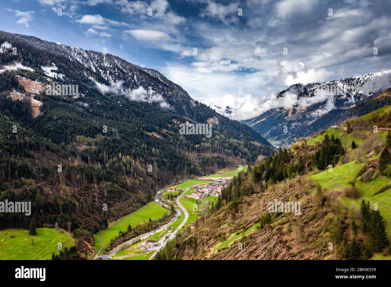Veduta aerea della valle con verdi pendici delle montagne d'Italia tempo nuvoloso, Trentino, gli alberi caduti dal vento, enormi nuvole su un Foto Stock