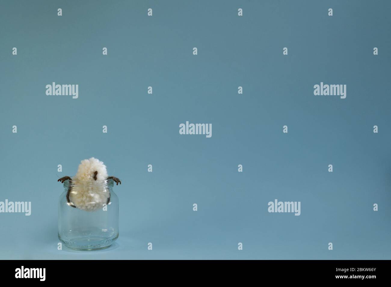 Un pulcino giocattolo di un pollo si siede a peping fuori dal vaso che stringe le zampe sopra i bordi. Foto Stock