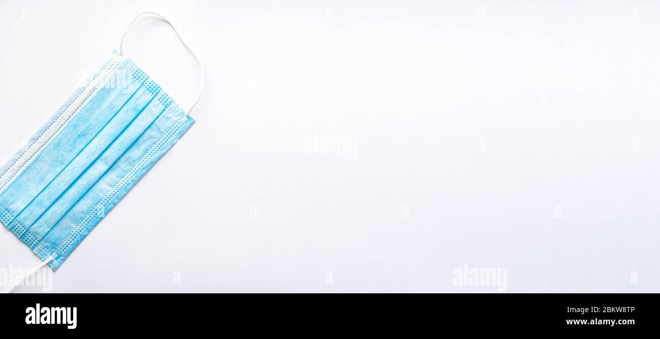 Maschera protettiva monouso blu per uso medico su uno spazio di copia su sfondo bianco. Una medicazione chirurgica chiude la bocca e il naso. Sanità, medicina, covid Foto Stock