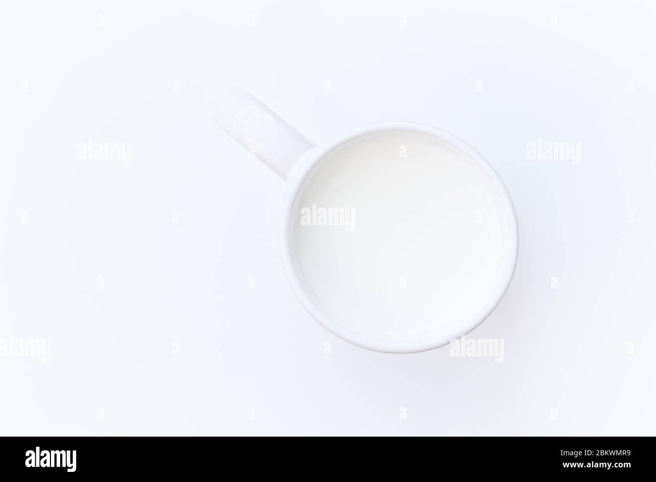 Tazza bianca con latte su una superficie bianca liscia. Linea orizzontale. Immagine concettuale astratta. Foto Stock