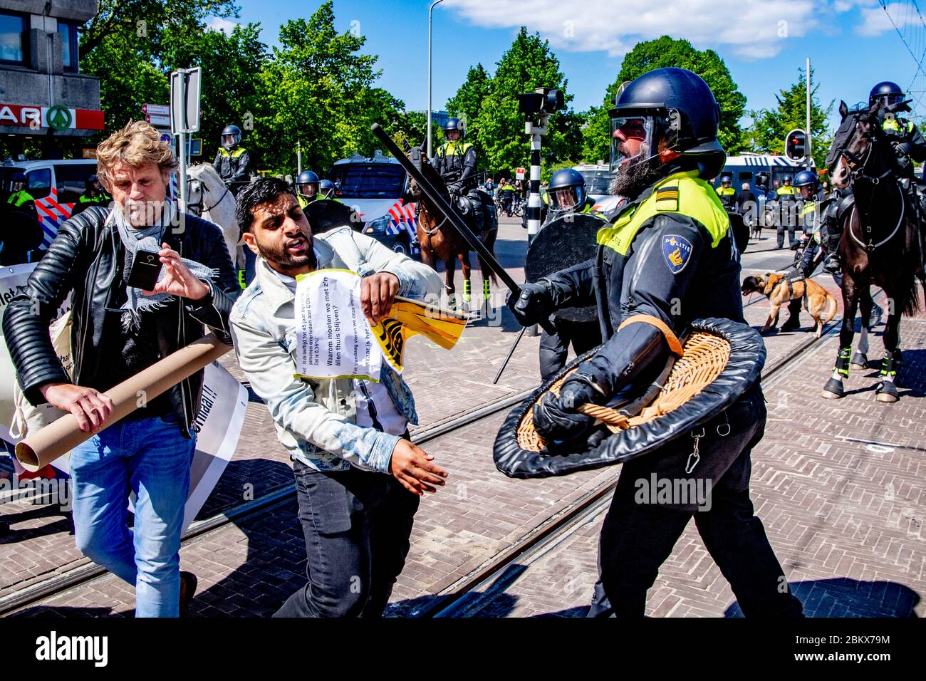 Un dimostratore che si scontrava con un poliziotto durante la protesta.decine di attivisti anti-blocco sono stati arrestati mentre dimostravano contro le misure contro il virus corona all'Aia. Foto Stock