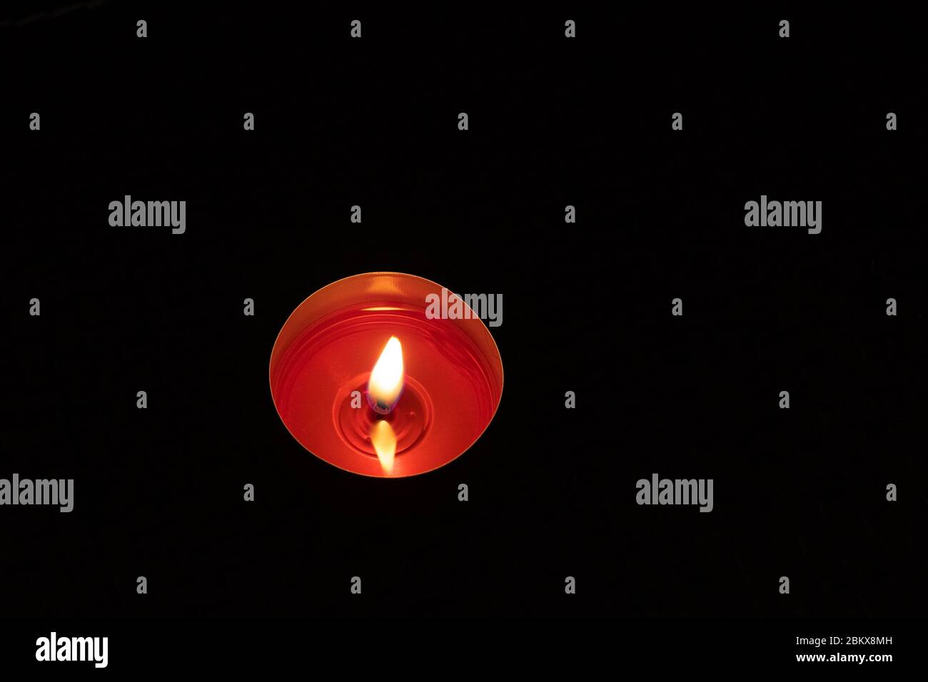 Candela singola su sfondo da vicino. Candela rossa bruciante su uno sfondo nero. Foto Stock