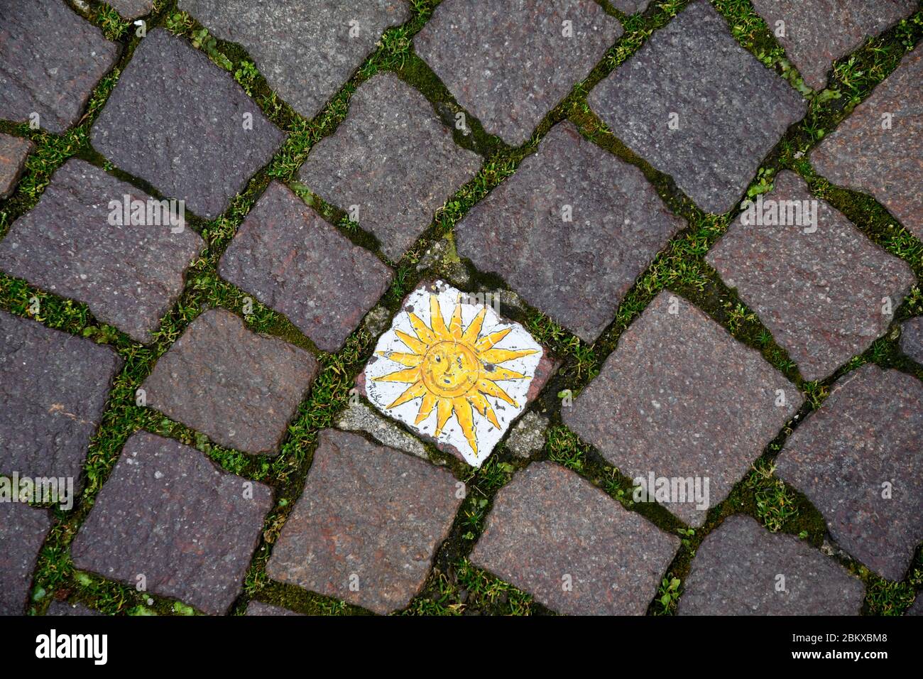 Primo piano di un pavimento in strada a cubetti di porfido nel centro storico di Bardolino con decorazione dipinta a mano raffigurante un sole, Verona, Veneto, Italia Foto Stock