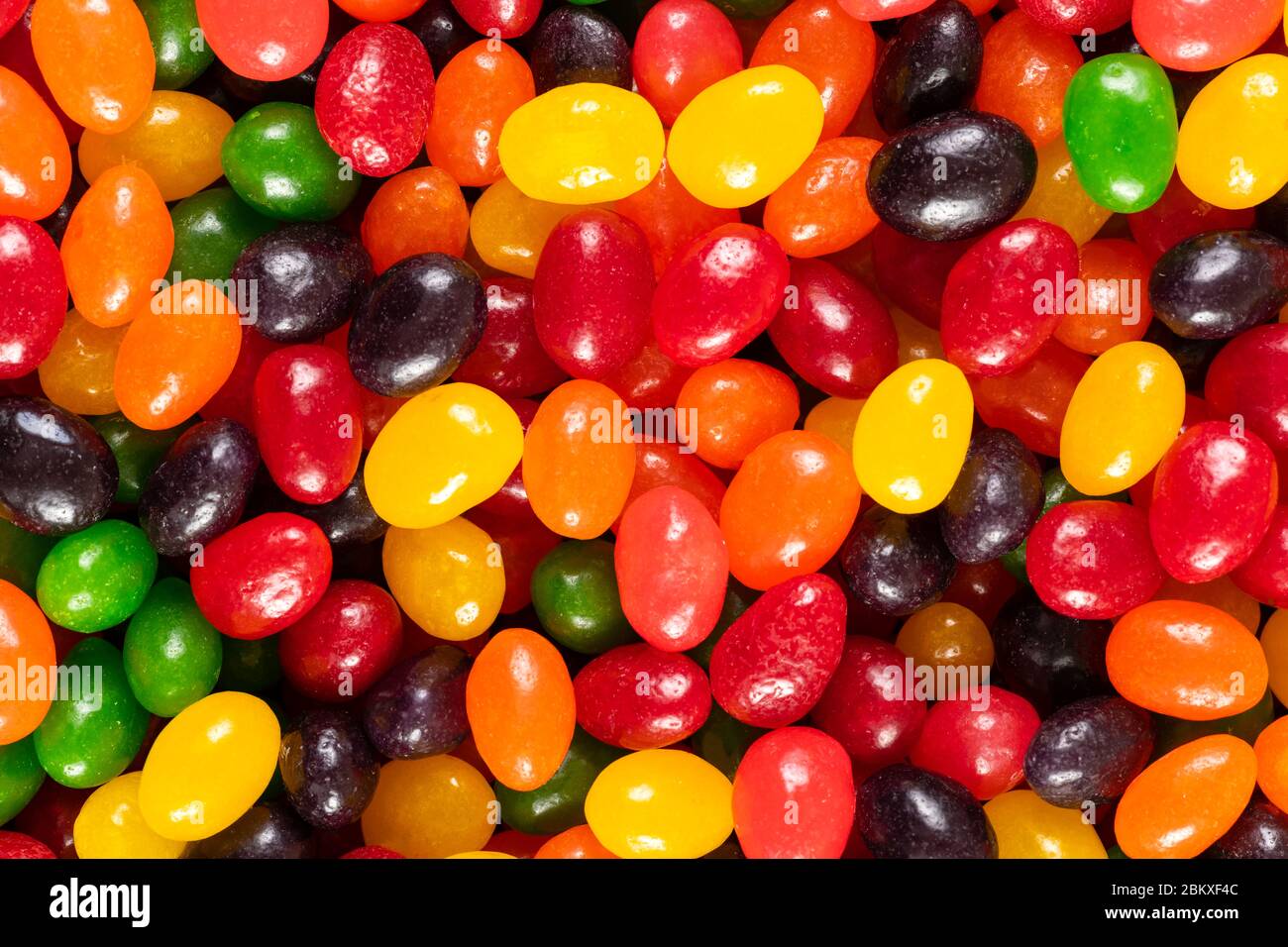 Assortiti colorati fagioli di gelatina nero, rosso, verde, giallo e arancione, dolci sfondo caramella, cibo spazzatura bambini. Foto Stock