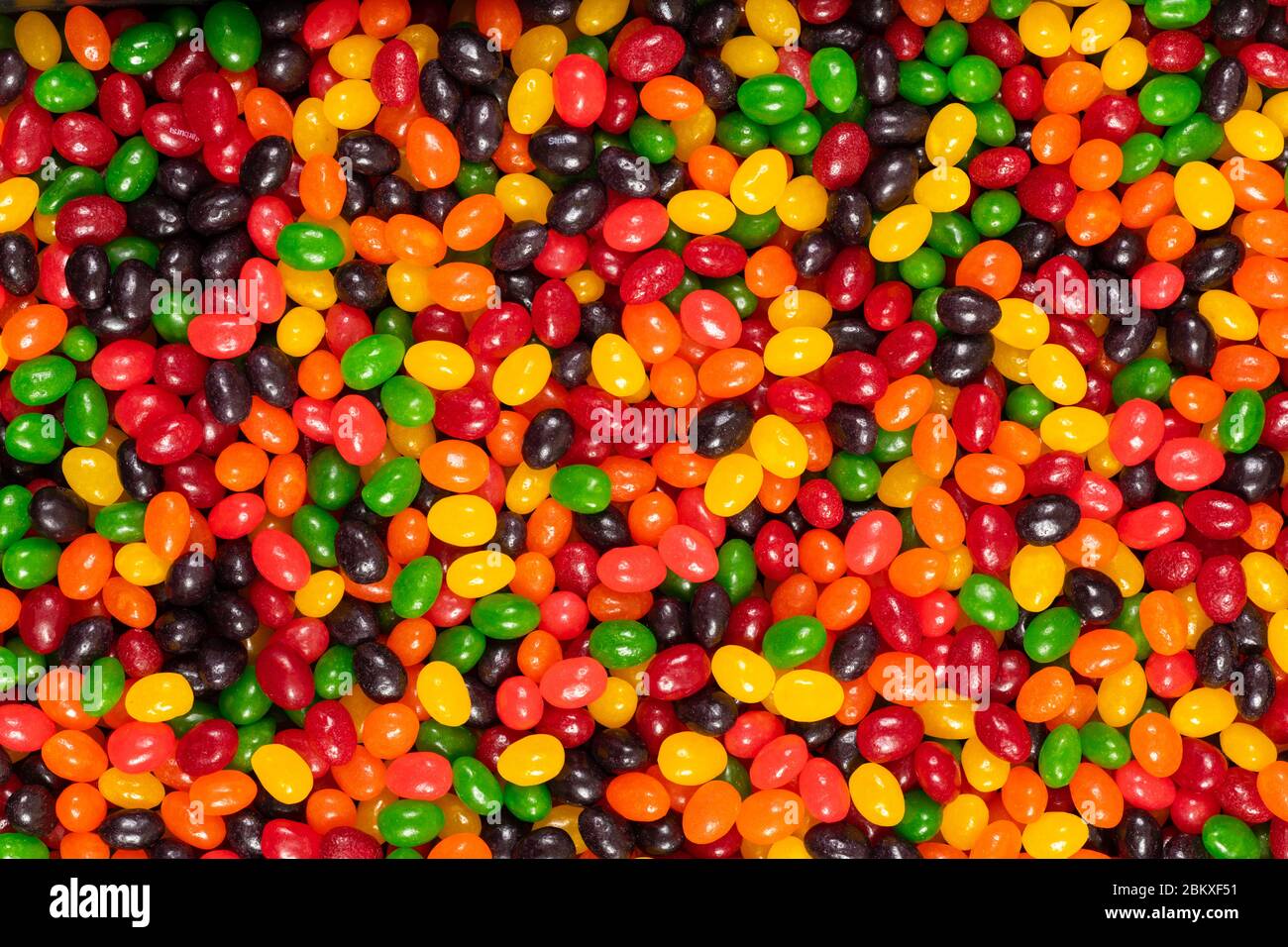 Assortiti colorati fagioli di gelatina nero, rosso, verde, giallo e arancione, dolci sfondo caramella, cibo spazzatura bambini. Foto Stock