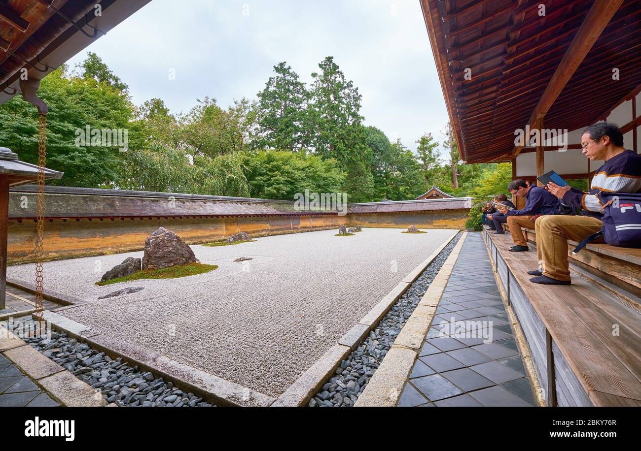 Popoli sulla veranda del Hojo, l'ex residenza del prete principale contempla il giardino Zen - il paesaggio secco (karesansui) giardino di roccia. Ryoan Foto Stock