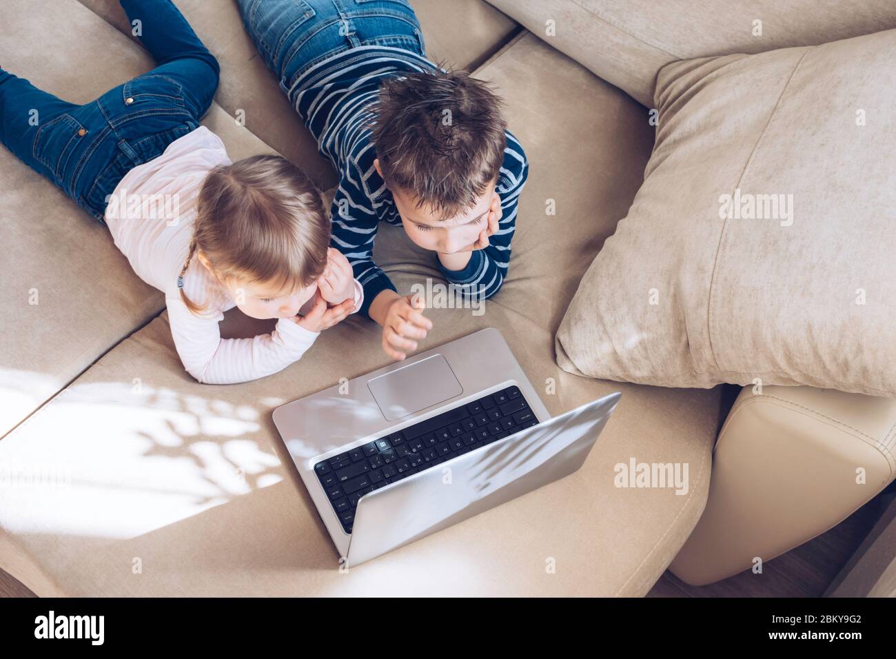 Bambini che studiano a casa utilizzando lezioni online su laptop. Bambini che guardano i cartoni animati online. Quarantena a casa. Formazione a distanza, formazione online. Foto Stock