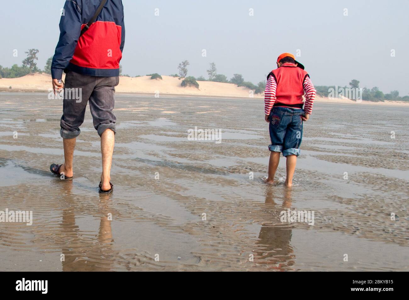 Padre e figlio a piedi sulla spiaggia di mare in una giornata di sole a Chandipur, Orissa, India. Foto Stock