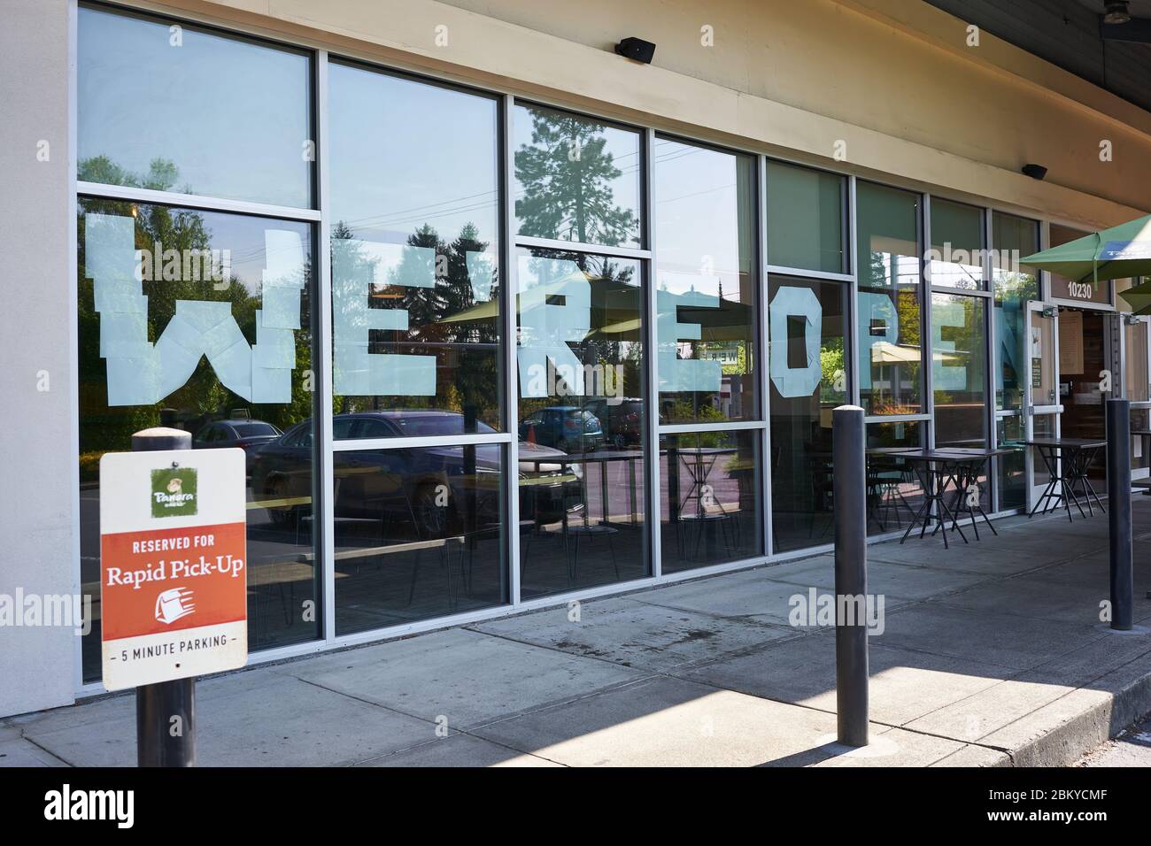 "SIAMO APERTI" - un grande cartello è visibile in un luogo di Panera pane aperto per andare e consegna. Panera Bread Company è una catena di caffè da forno. Foto Stock