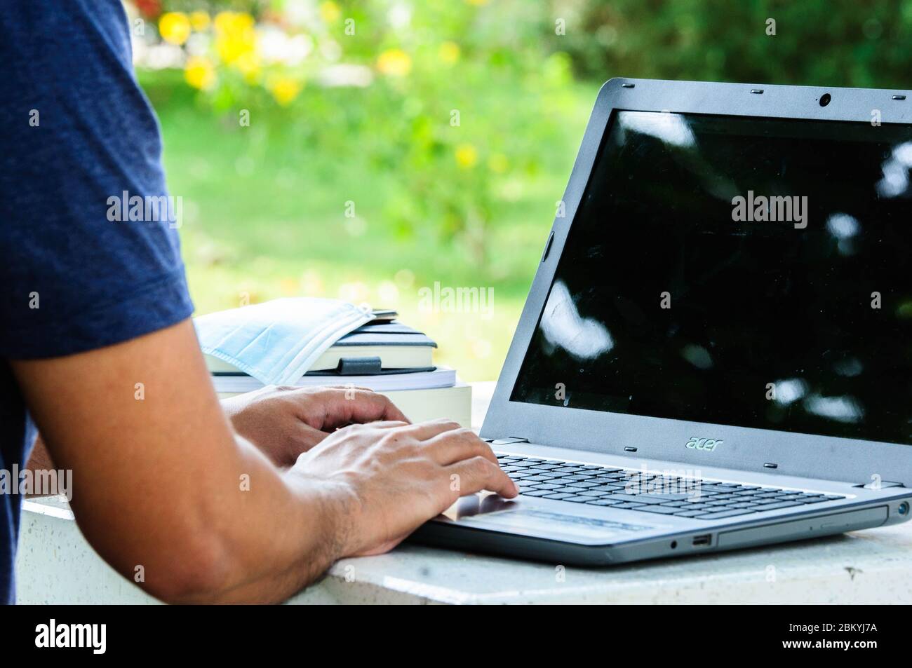 Una persona che lavora o impara online con un computer portatile sulla scrivania nel giardino della casa. Foto Stock