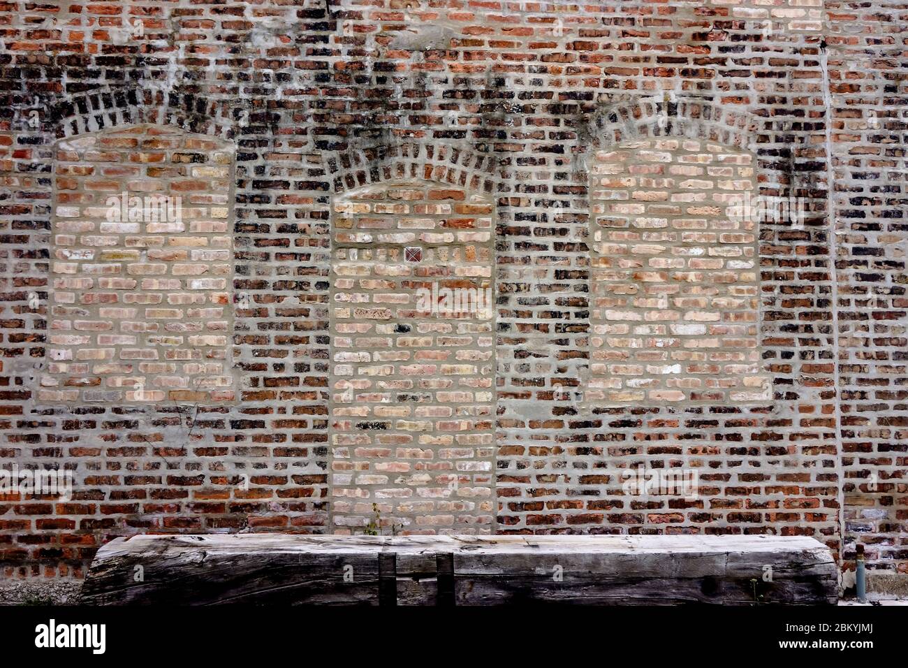 Multicolore vecchio muro di mattoni con finestre a legna e panca in legno Foto Stock