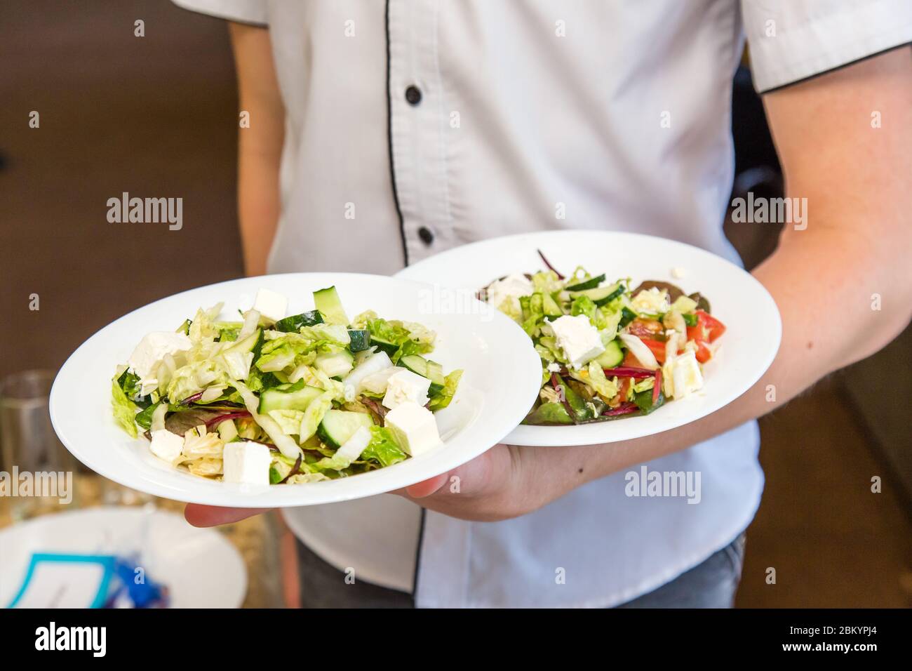 Il cameriere può tenere due piatti di insalata, lavorare sulla serviсе evento. Foto Stock