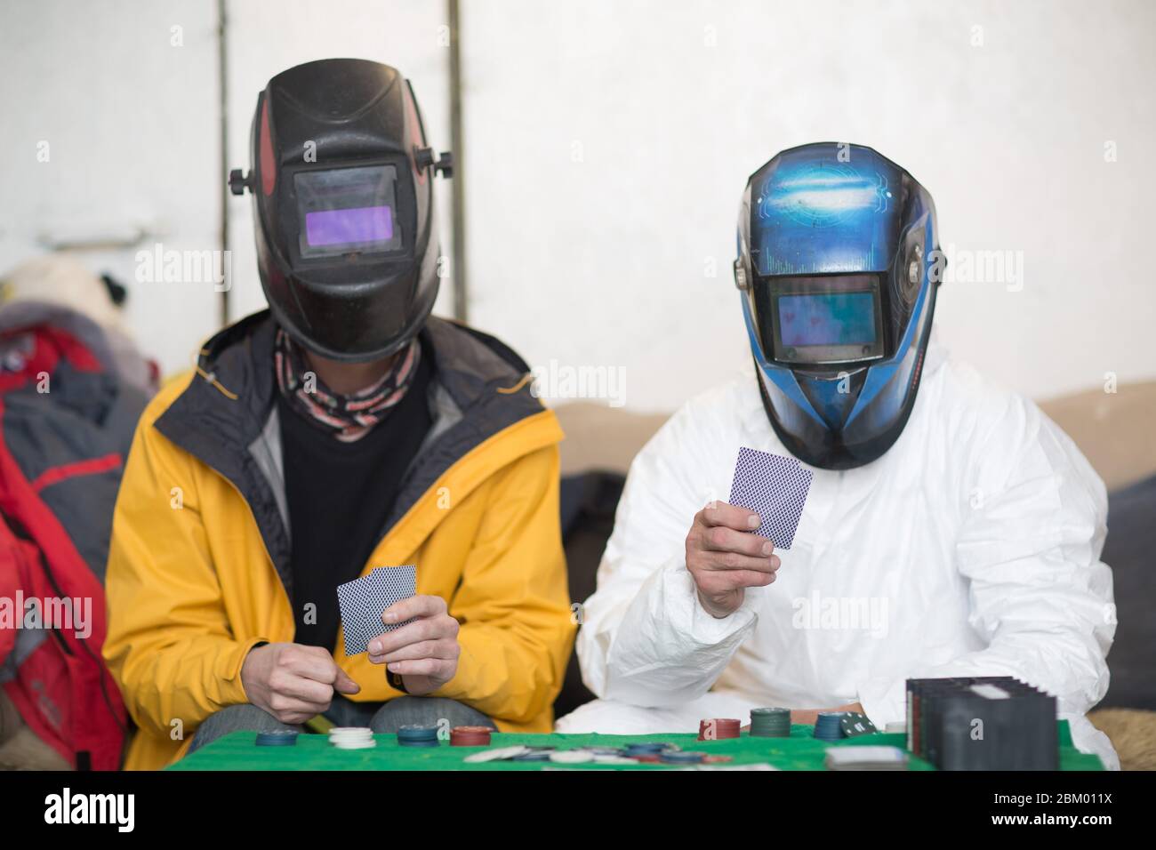 Due saldatori in maschere di saldatura giocare poker Foto Stock