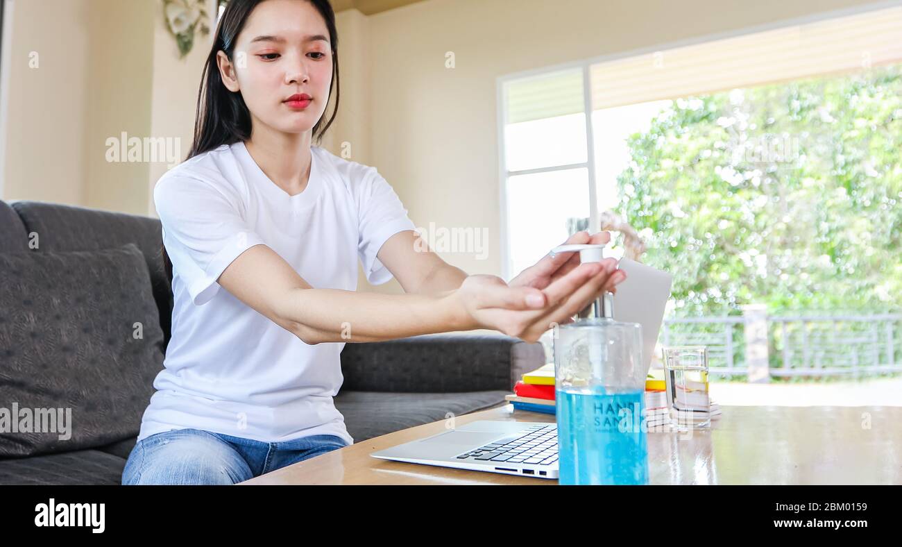 Asian Business donna che lavora da casa e lei è la pulizia delle mani con gel igienizzante per il coronavirus protettivo. È in quarantena a casa durante Foto Stock