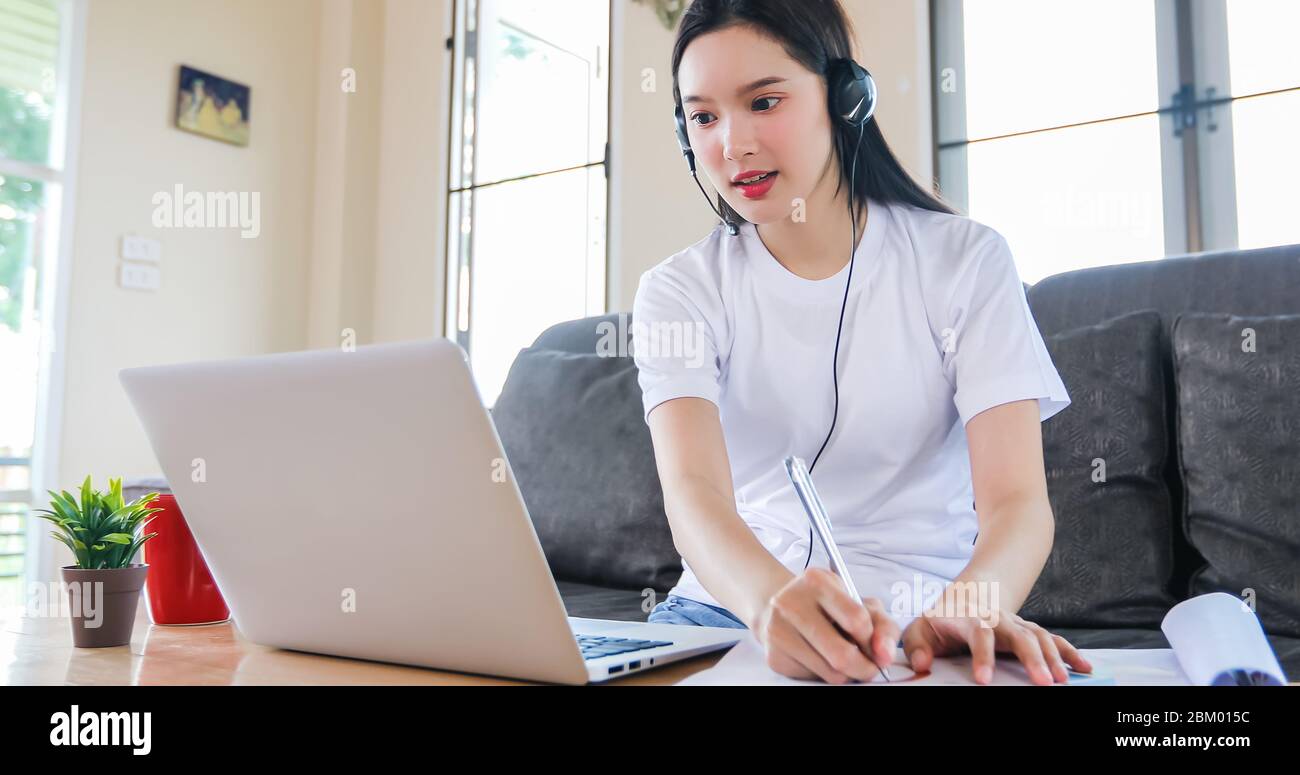 Asian Happy Woman studente indossare cuffie studio online guardare il webinar podcast su notebook ascoltare formazione corso di formazione conferenza chiamate e w Foto Stock