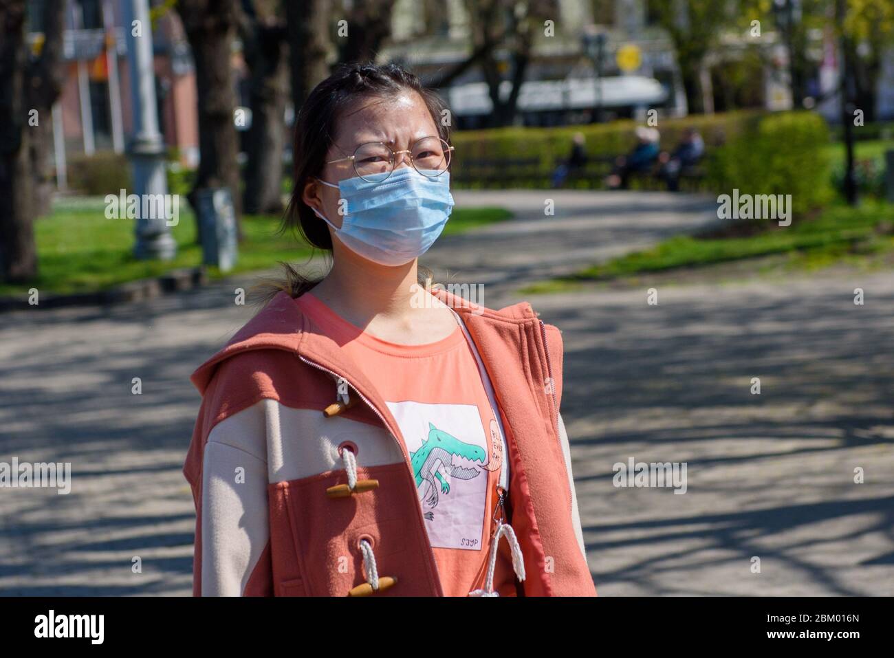 RIGA, LETTONIA. 4 maggio 2020. Donna asiatica, che indossa maschera protettiva viso cammina per strada nella città di riga. Foto Stock