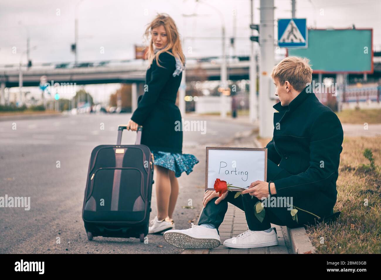 la separazione di uomo e donna. la ragazza con una valigia lascia il ragazzo. il giovane uomo sconvolto Foto Stock