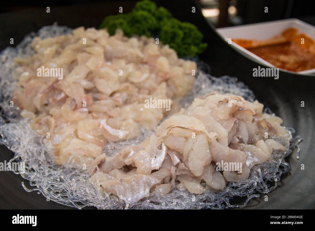 Una grande porzione di salmone crudo di pesce viene servita su un piatto nero. Foto Stock