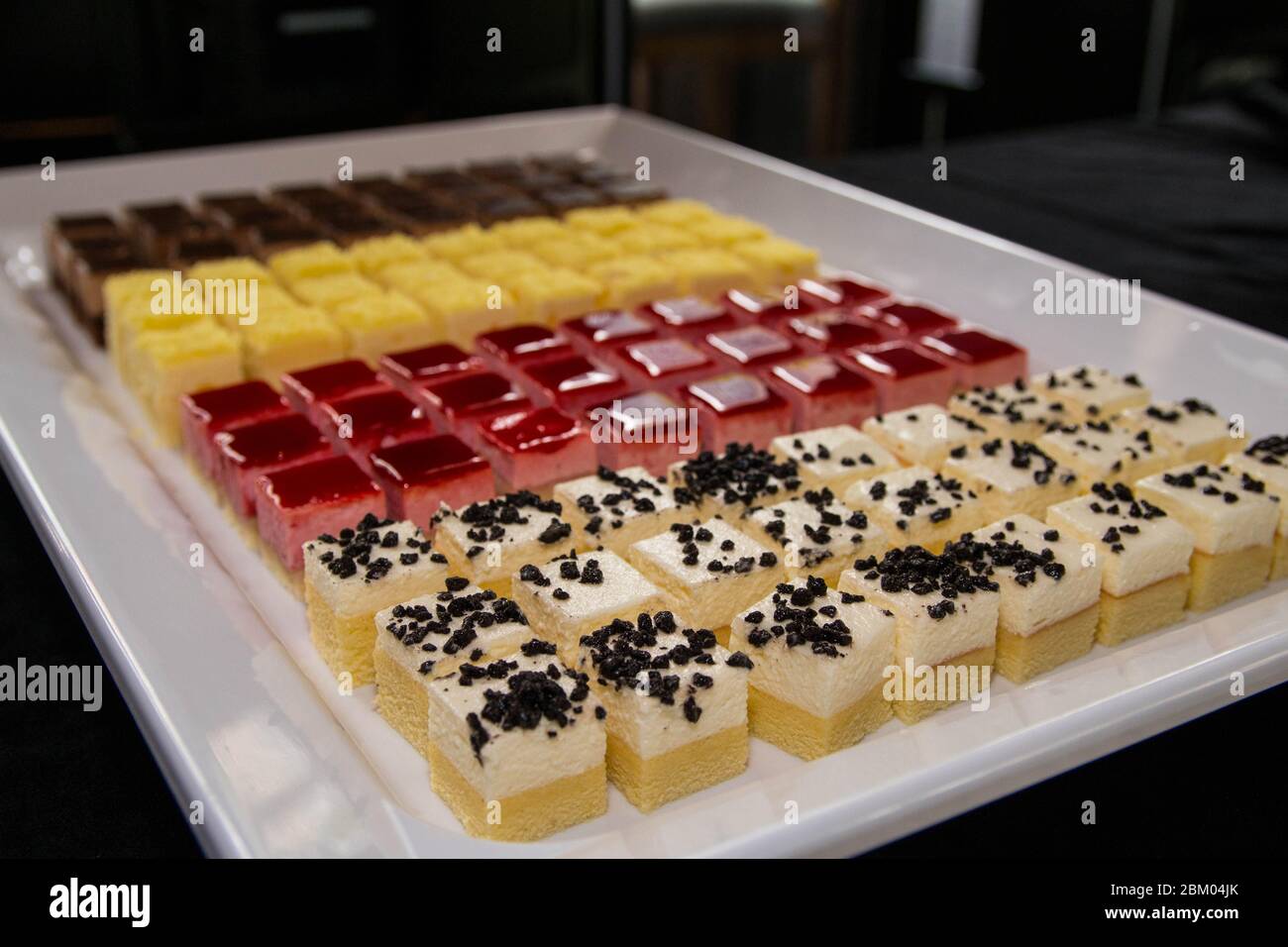 Mini fetta di torte colorate con molti sapori su un piatto bianco. Piccoli stuzzichini in un buffet di festa. Foto Stock