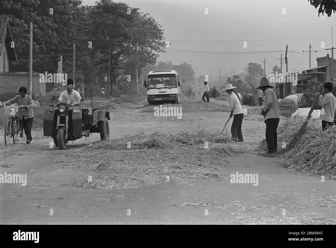 Nel 1996 gli abitanti del villaggio di Qian County Shaanxi battono il grano sull'autostrada Foto Stock