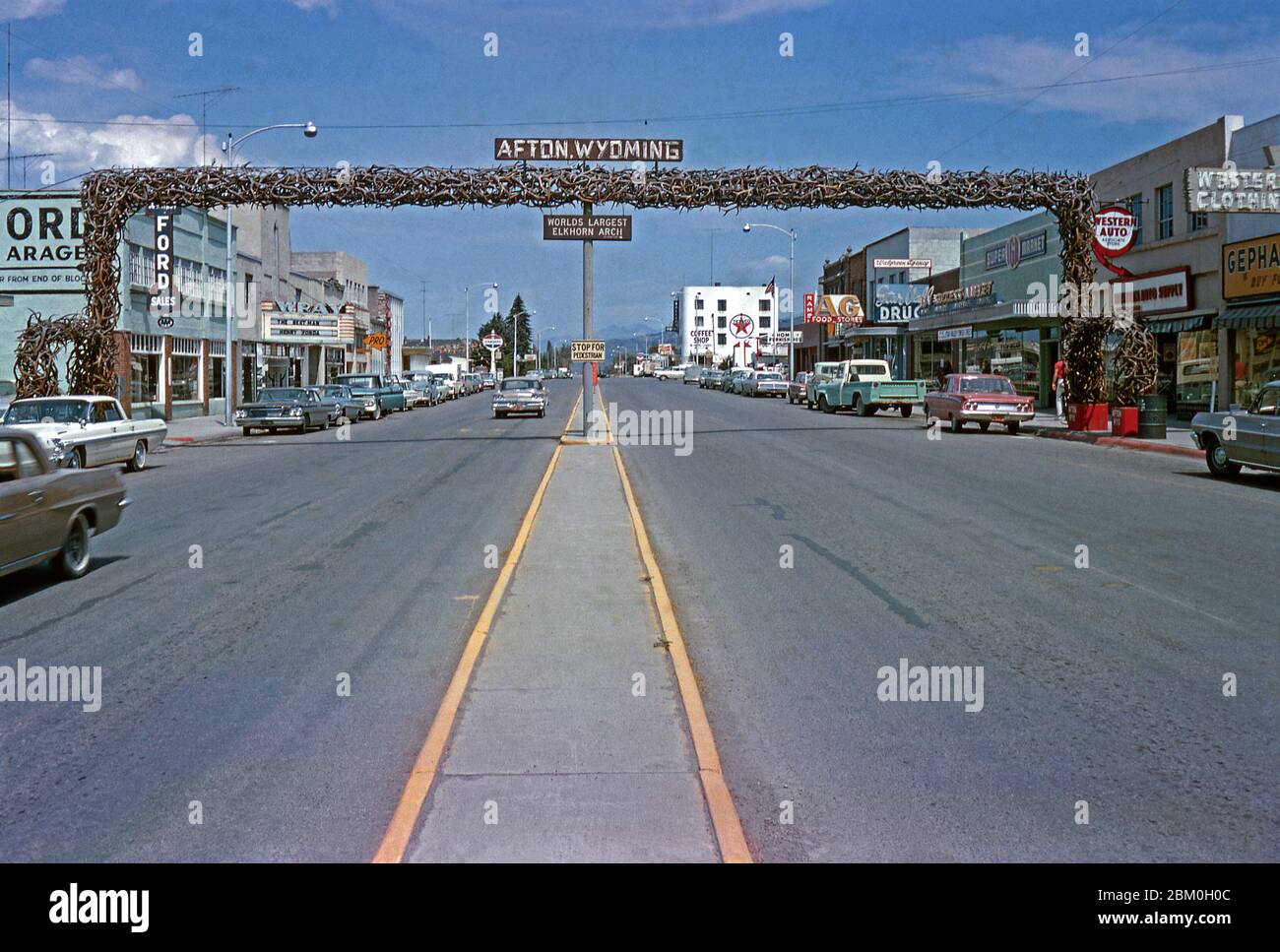 Il famoso arco elkhorn a Main Street, Afton, Lincoln County, Wyoming, USA 1964. È ancora il più grande arco del mondo fatto di antlers dell'alce. L'arco si estende per 75 m (23 piedi) attraverso le quattro corsie dell'autostrada 89 e comprende oltre 3000 formiche di alci. Negozi e un supermercato si trovano lungo la strada e c'è un garage Texaco e una concessionaria Ford. Il cinema Wray (al centro di sinistra) mostra "The Best Man" con Henry fonda, che è stato rilasciato quell'anno. Foto Stock