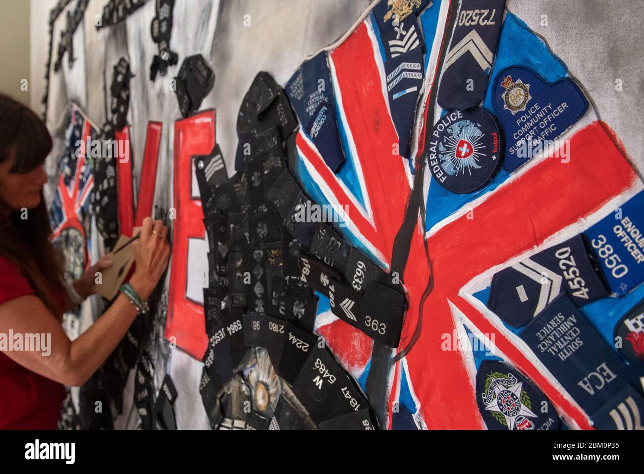 L'artista Sam Bailey aggiunge un tocco finale a un murale con il capitano Tom Moore e il sergente della guardia Grenadier Eric Presland, per celebrare il 75° anniversario del VE Day, nella sua casa a Northampton. Foto Stock