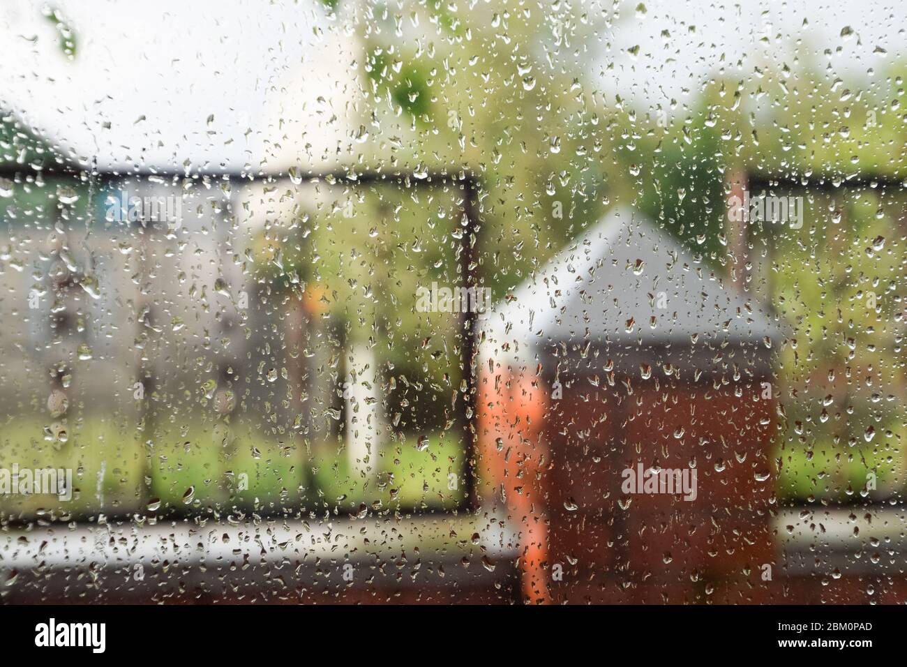 Raindrops nel riquadro della finestra. Sfondo sfocato fuori dalla finestra sotto la pioggia. Foto Stock