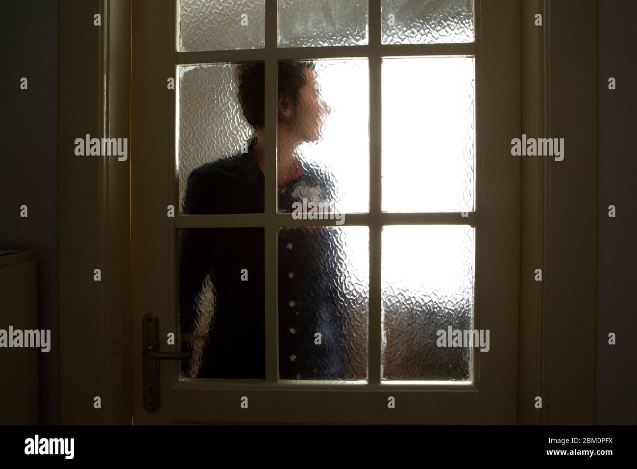 Una fotografia di un profilo di persone scattato attraverso un vetro della porta sfocato Foto Stock