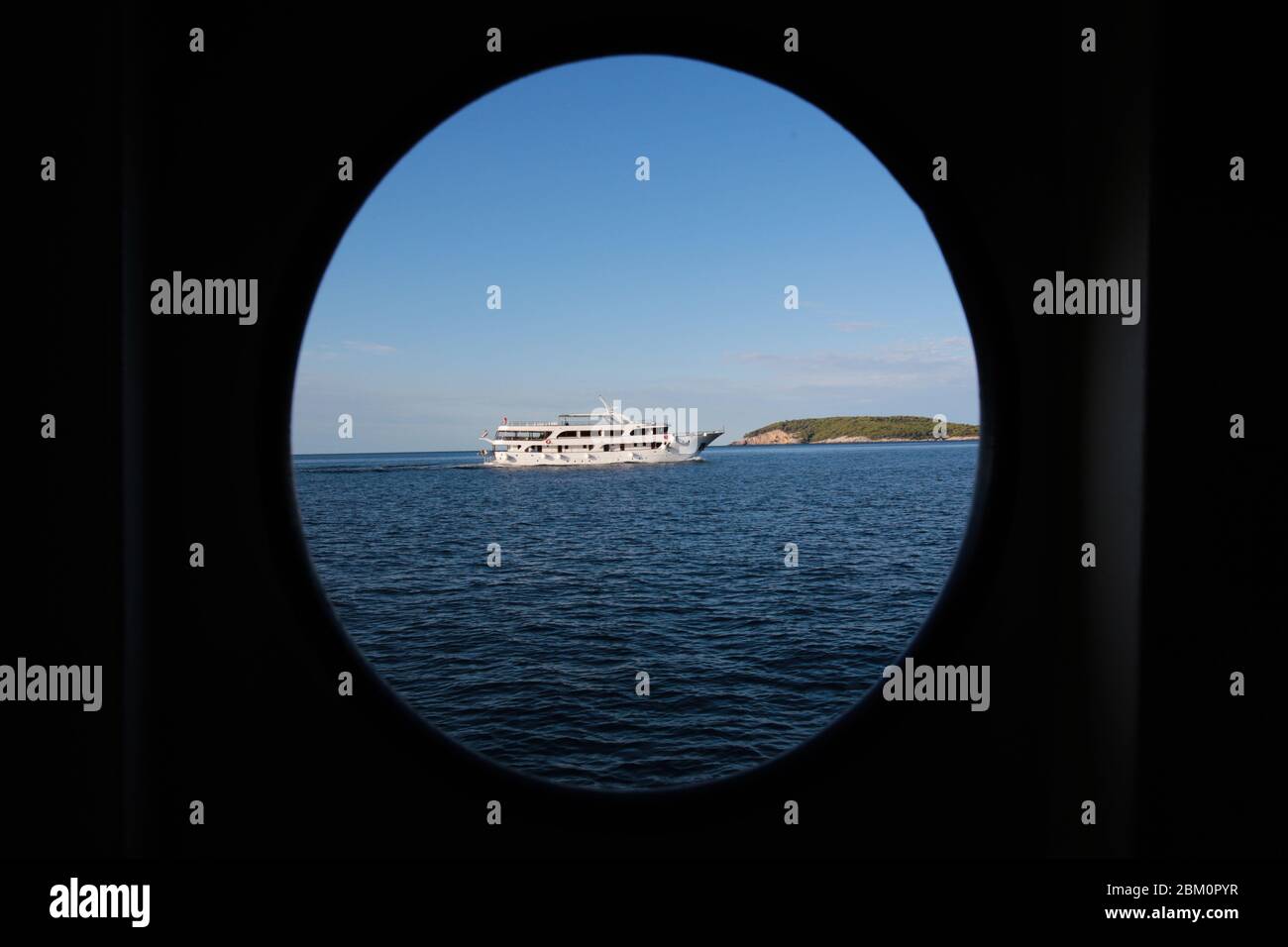 Una nave turistica che naviga fotografata attraverso una silhouette di una finestra di navi Foto Stock