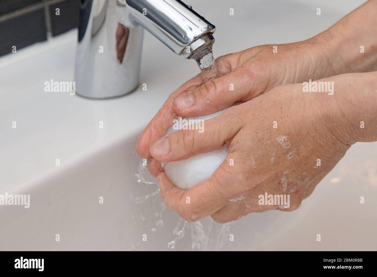 mani con sapone sotto l'acqua corrente Foto Stock