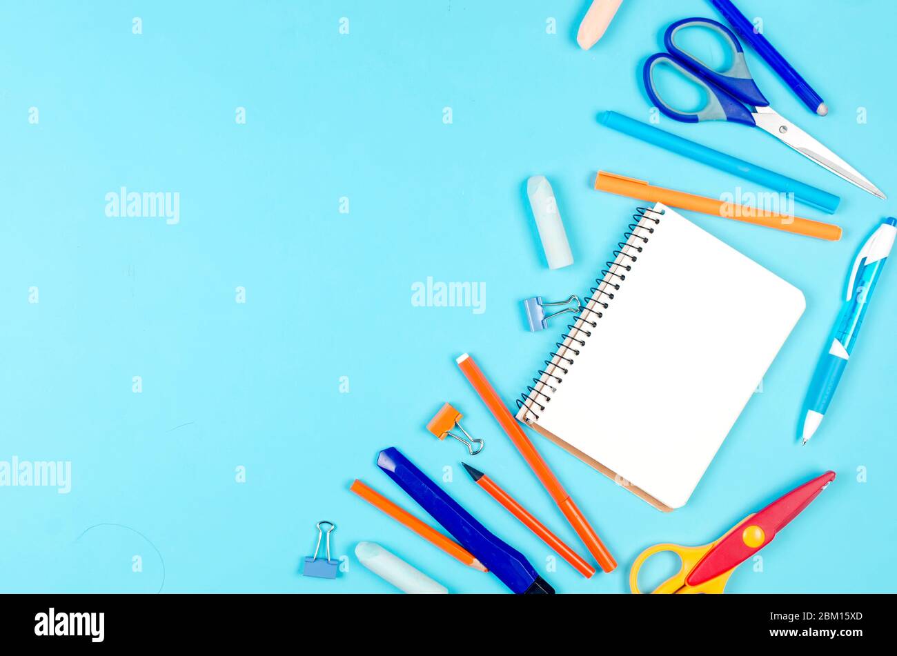 Notebook, blu e arancione forniture scuola su sfondo blu. Concetto di istruzione. Vista dall'alto con spazio per la copia. Mockup, flatlay Foto Stock