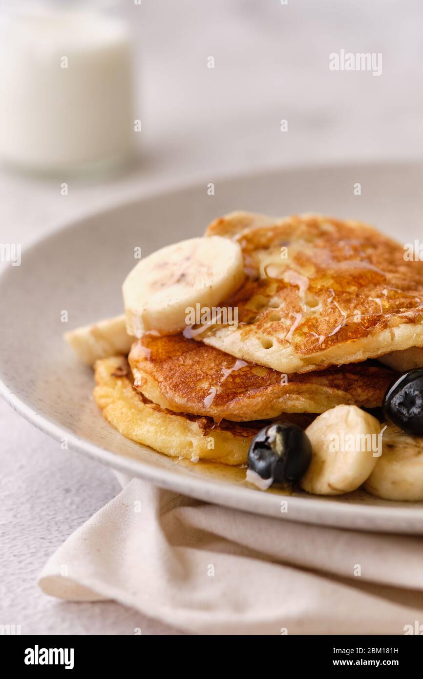 Pile di pancake al latticello con banane, sciroppo e mirtilli. Foto Stock