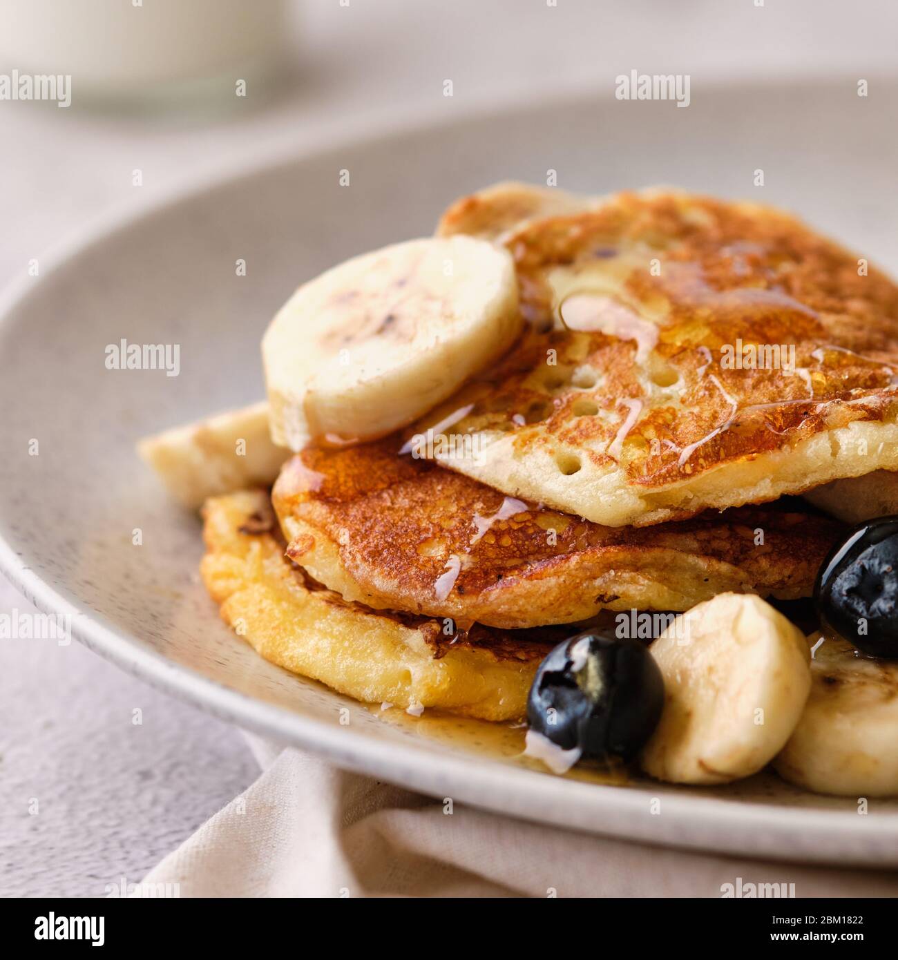 Pile di pancake al latticello con banane, sciroppo e mirtilli. Foto Stock