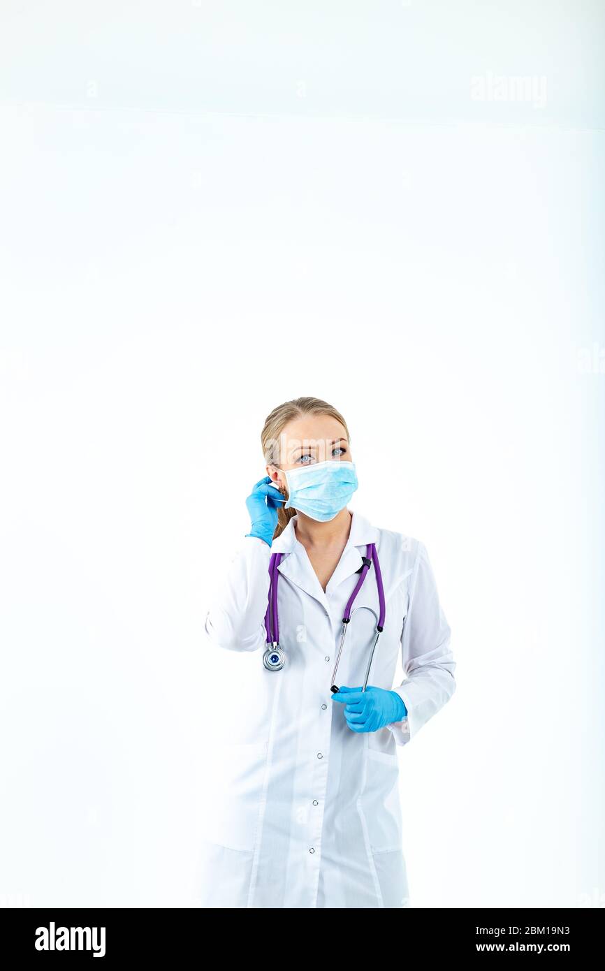 l'infermiere del medico mette su una maschera protettiva. Un infermiere in una maschera respiratoria. Indossare le maschere. Indossare guanti. Bello medico biondo mostra come indossare un protec Foto Stock