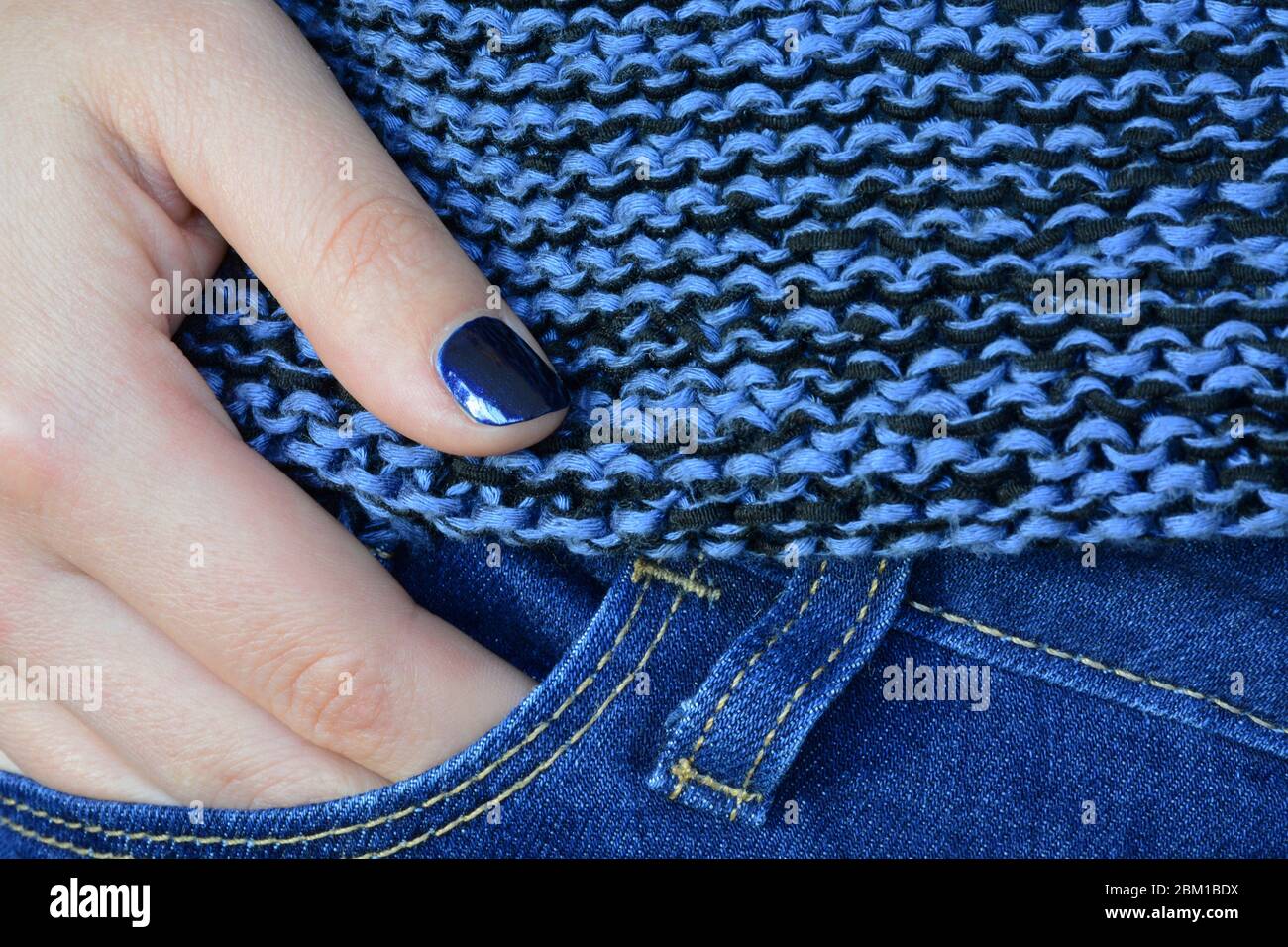 Classico colore blu tonalità. Donna che indossa jeans blu, maglione e smalto per unghie Foto Stock