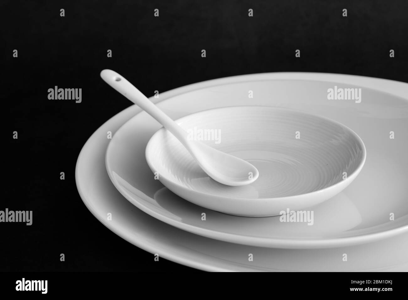 Set di piastre con cucchiaio su tavolo nero Foto Stock