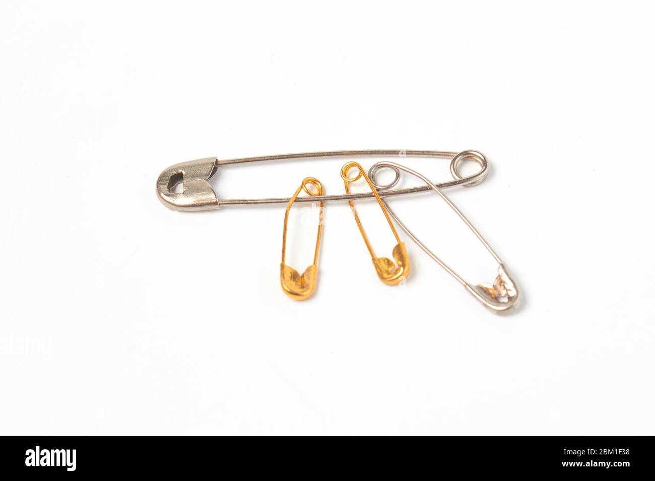 diversi pin di acciaio e oro su un isolato di sfondo bianco Foto Stock
