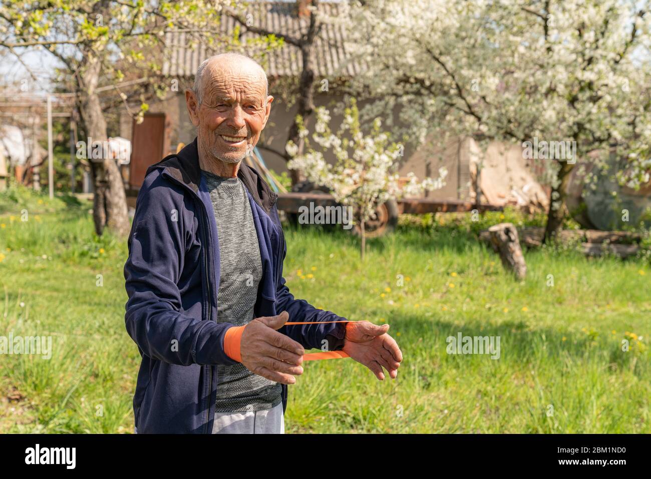 Vecchio uomo che fa esercizi di fitness con elastico banda di resistenza. Formazione senior con elastico Foto Stock