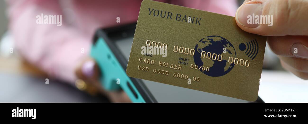 Le dita maschili tengono la carta di credito sopra il terminale Foto Stock