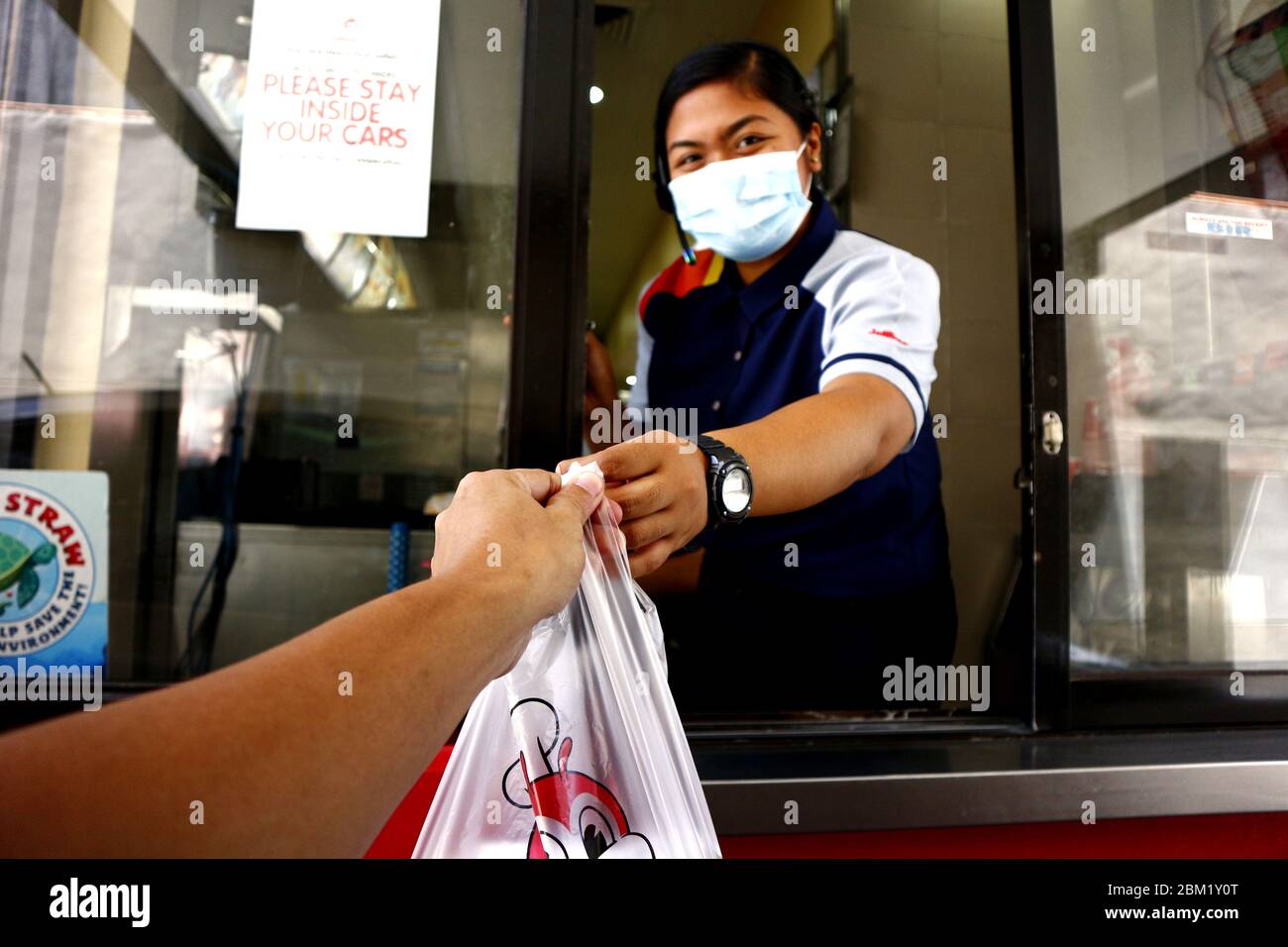 Antipolo City, Filippine - 5 maggio 2020: Dipendente di un fast food ristorante dare un ordine del cliente al drive thru finestra durante il Covid 19 viru Foto Stock