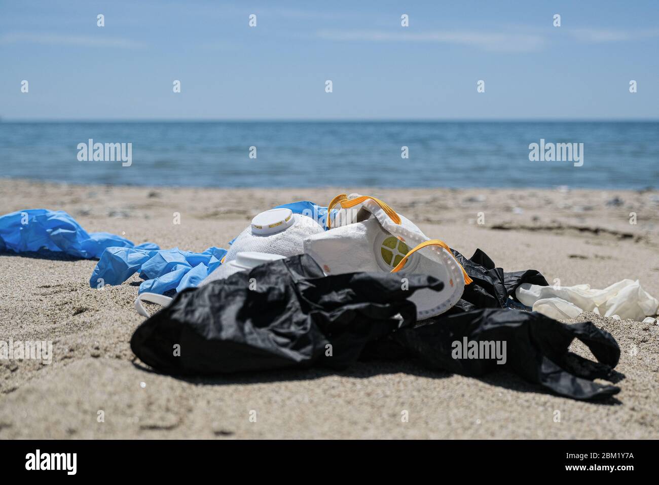 Maschera virus e guanti di plastica spazzatura sulla costa del mare, inquinamento da coronavirus Foto Stock
