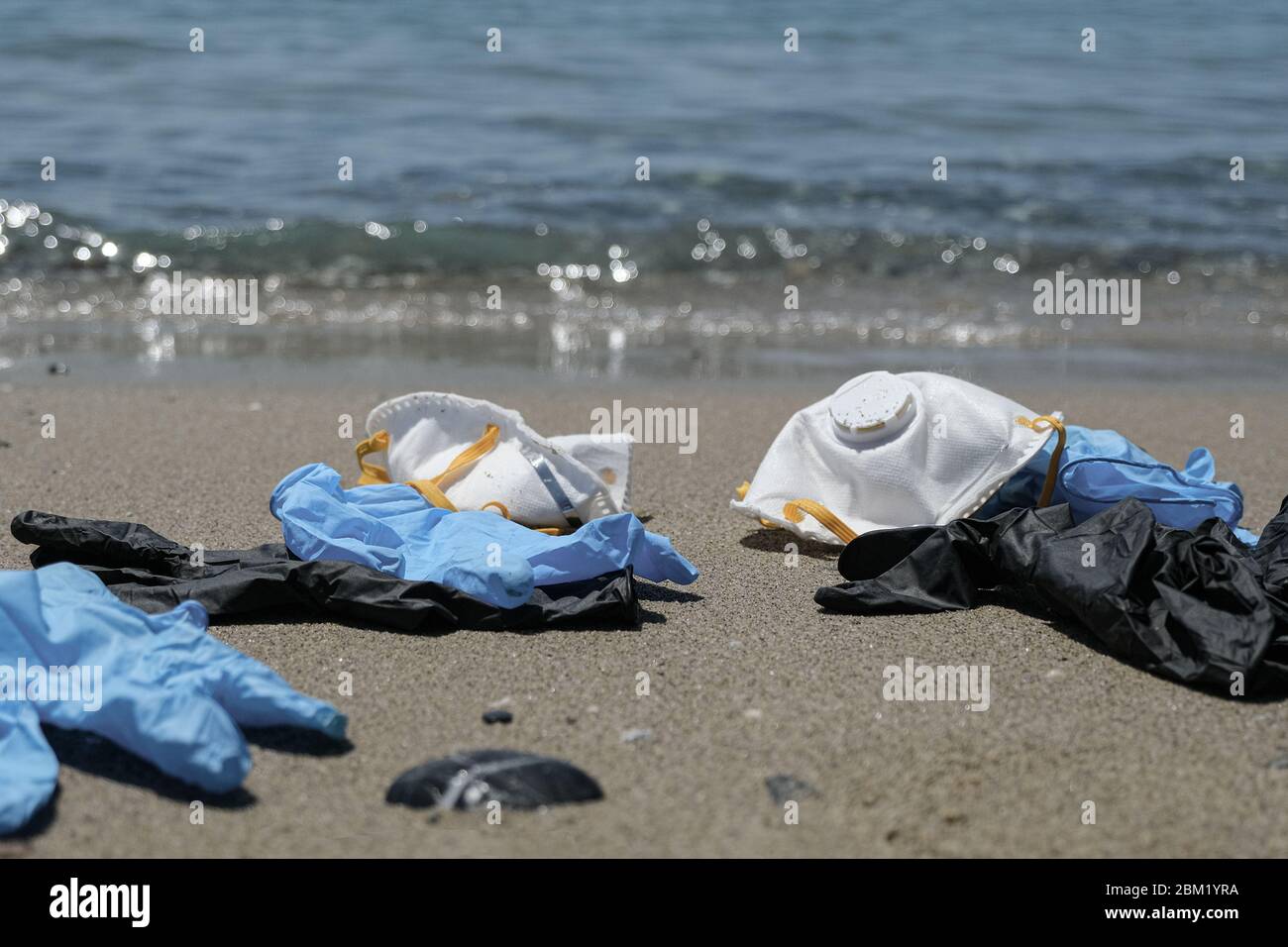 Maschera antivirus protettiva e guanti di plastica spazzatura rifiuti sulla spiaggia sabbiosa, malattia da inquinamento da cocvidi coronavirus Foto Stock