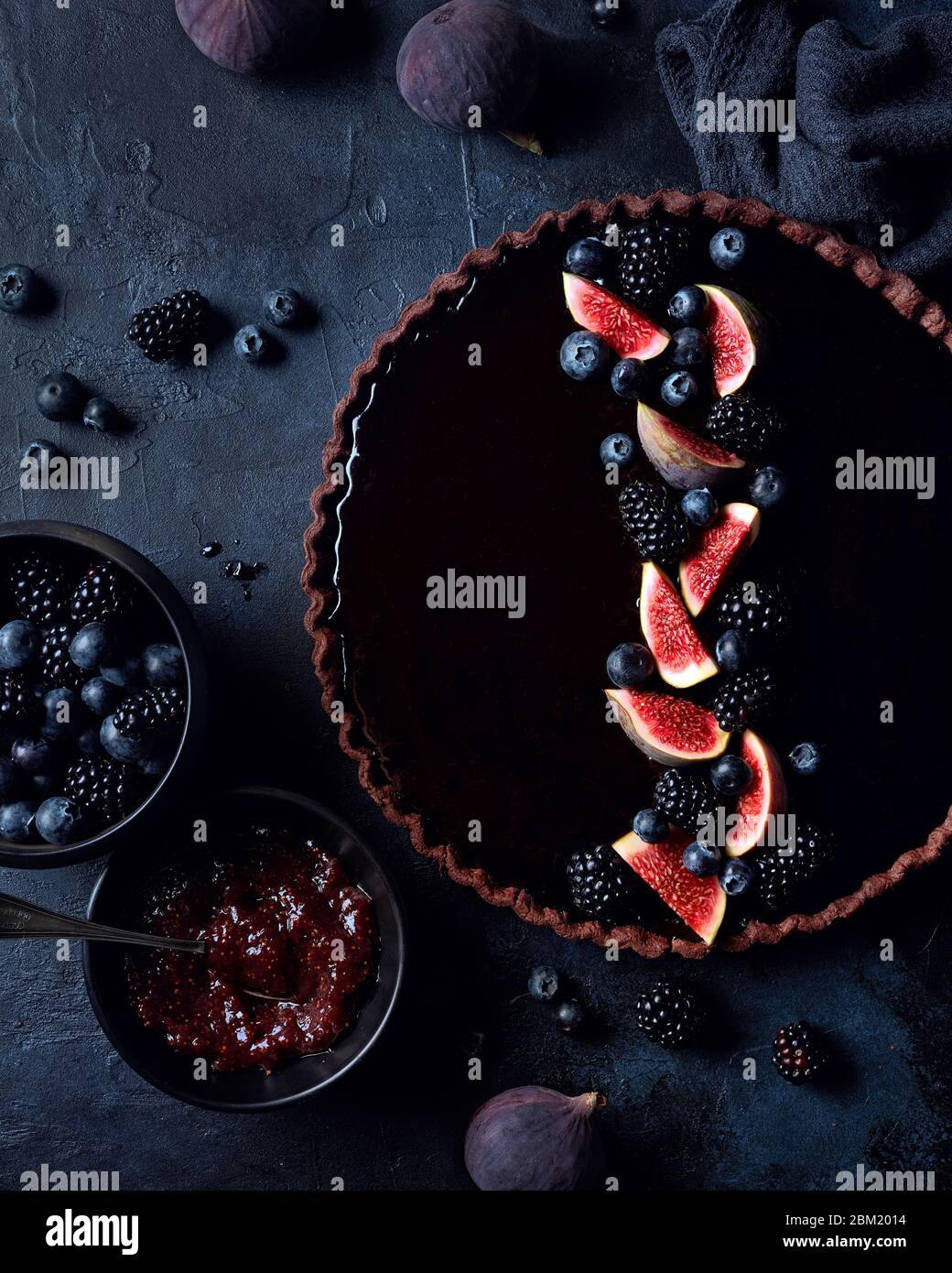 Torta al cioccolato fondente e fichi con frutti di bosco freschi su sfondo blu Foto Stock