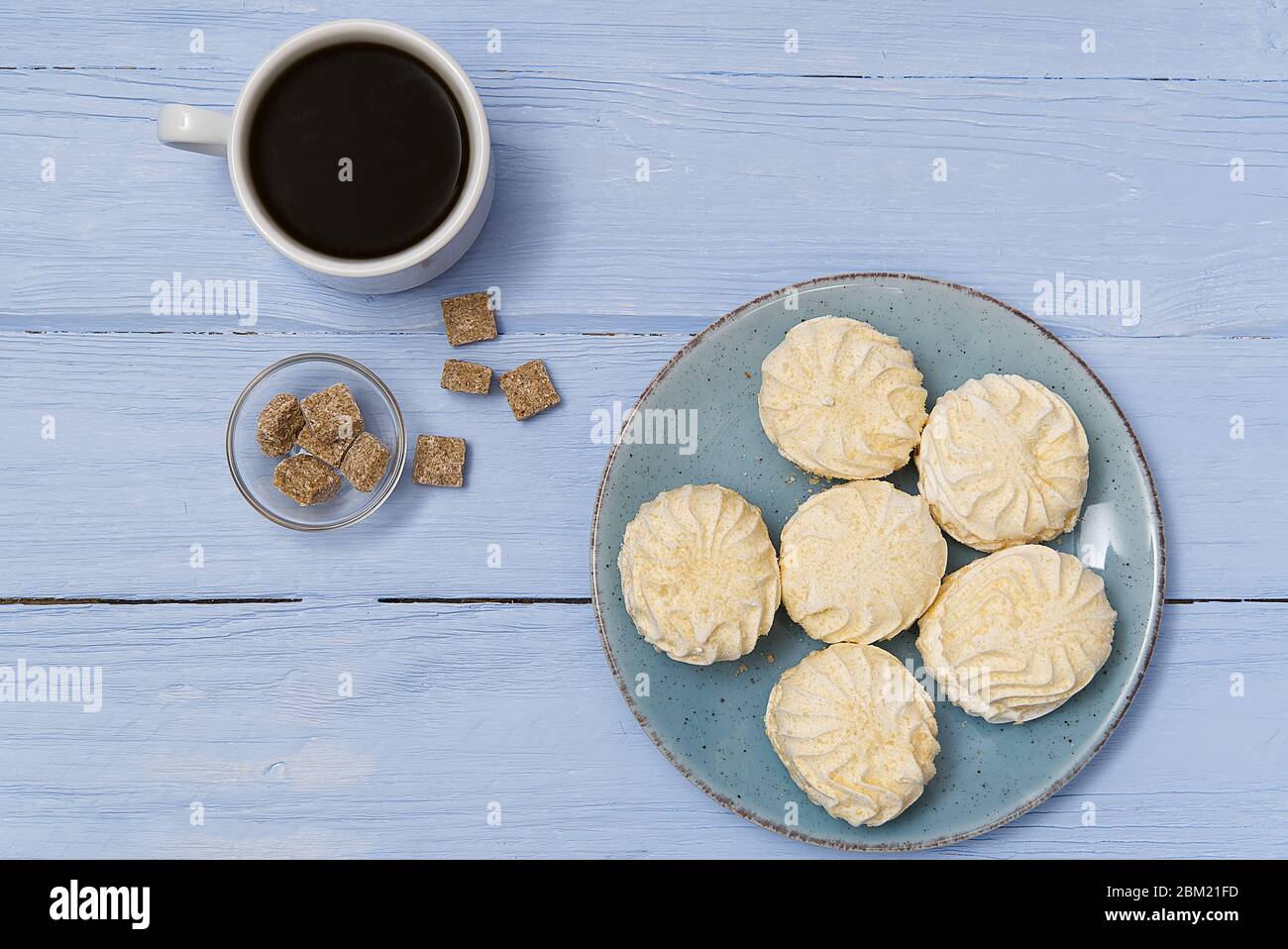 Tazza di caffè americano e zephyr o marshmallow fatti in casa in un piatto  blu su sfondo di legno blu chiaro Foto stock - Alamy