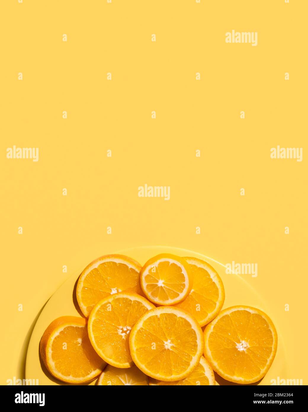 Succose fette di arancio sopra su un piatto giallo. Su sfondo giallo. Vista dall'alto. Foto Stock
